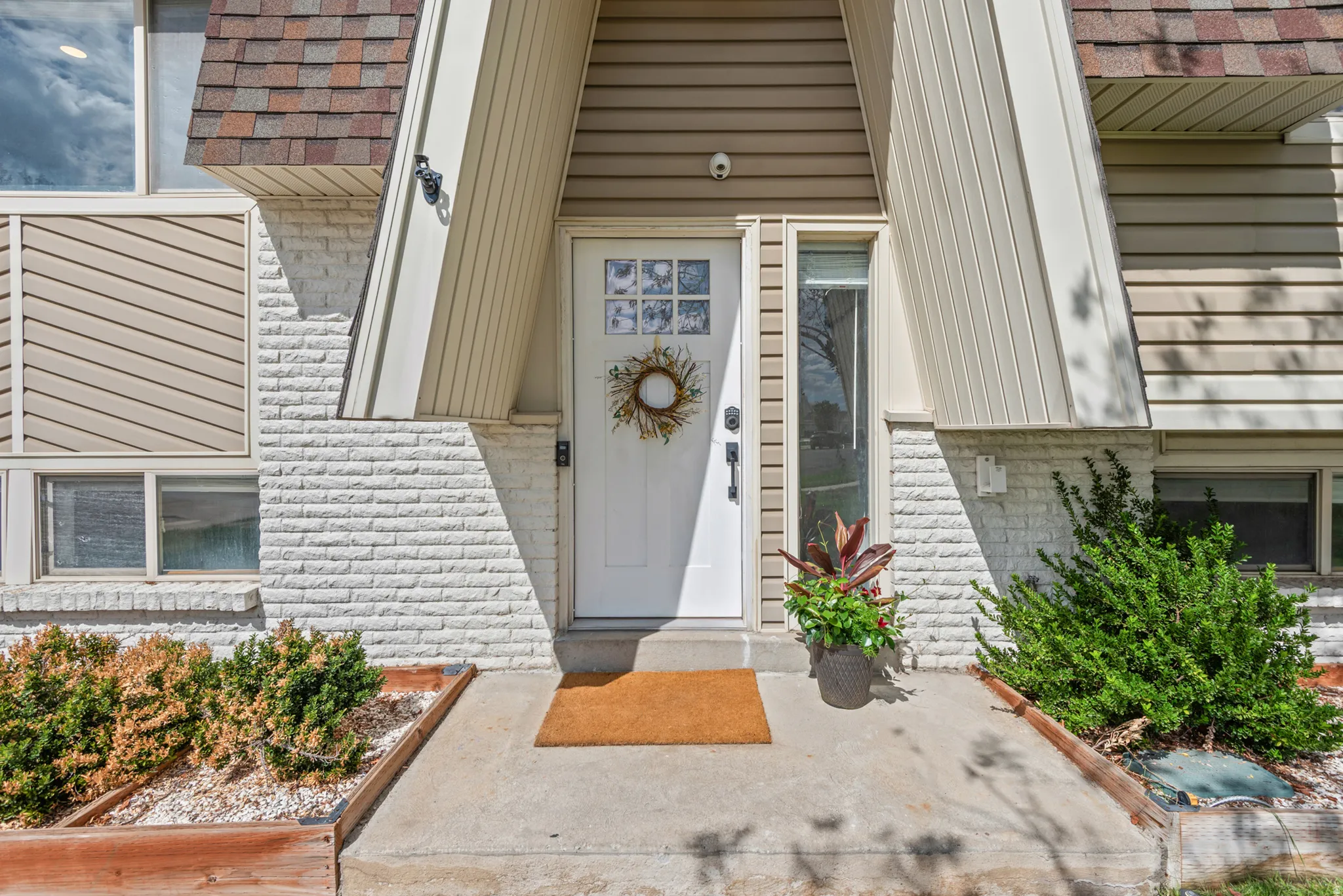 White brick facade and tan siding with a contrasting shingle roof