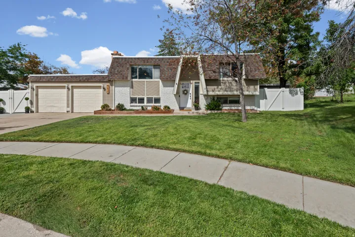 Split-level residence featuring a two-car garage, white painted brick exterior, and a dormer roof