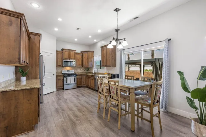 Kitchen featuring wood-finish cabinetry, stainless steel appliances, granite countertops, and wood-finish flooring