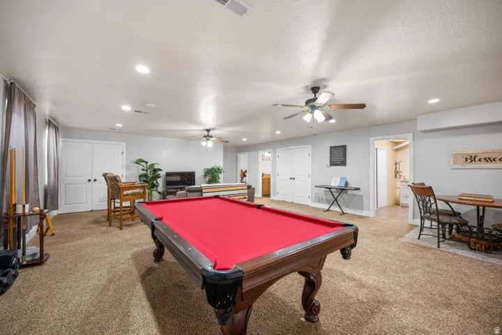 Expansive carpeted room with recessed lighting, ceiling fans, and double-door storage
