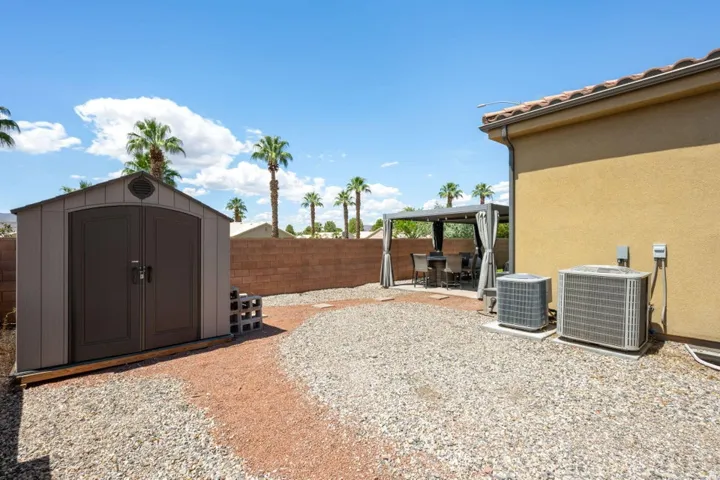 Gravel hardscaping, privacy wall, and a built-in storage shed