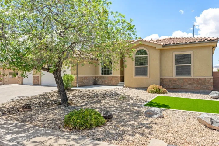 Stucco exterior with a tiled roof, stone accents, arched window, and drought-tolerant landscaping