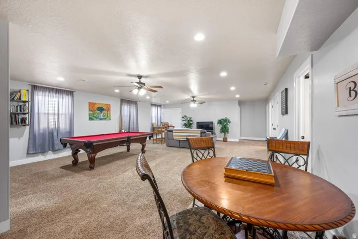 Spacious recreation room featuring recessed lighting, ceiling fans, and neutral carpeting