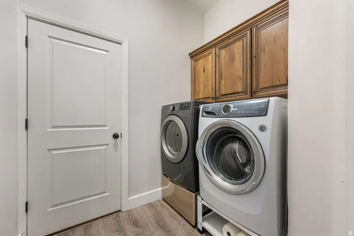 Wood-finish flooring, paneled interior door, overhead wood cabinetry, and neutral wall tones