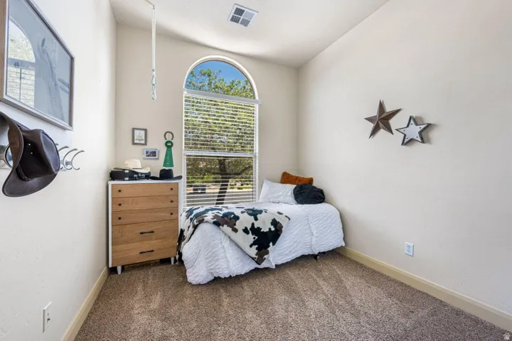Arched window with integrated blinds, light neutral wall paint, and textured carpet flooring