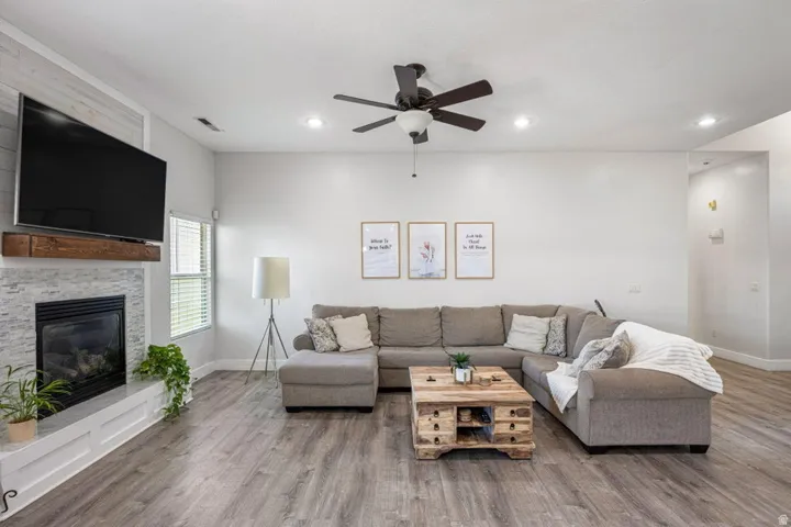 Living area with wood-finish flooring, recessed lighting, and a ceiling fan