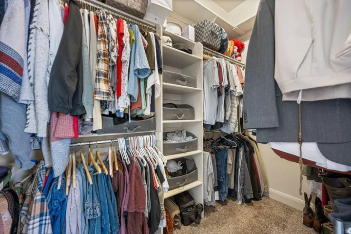 Built-in closet system featuring white shelving, multiple hanging rods, and integrated storage compartments