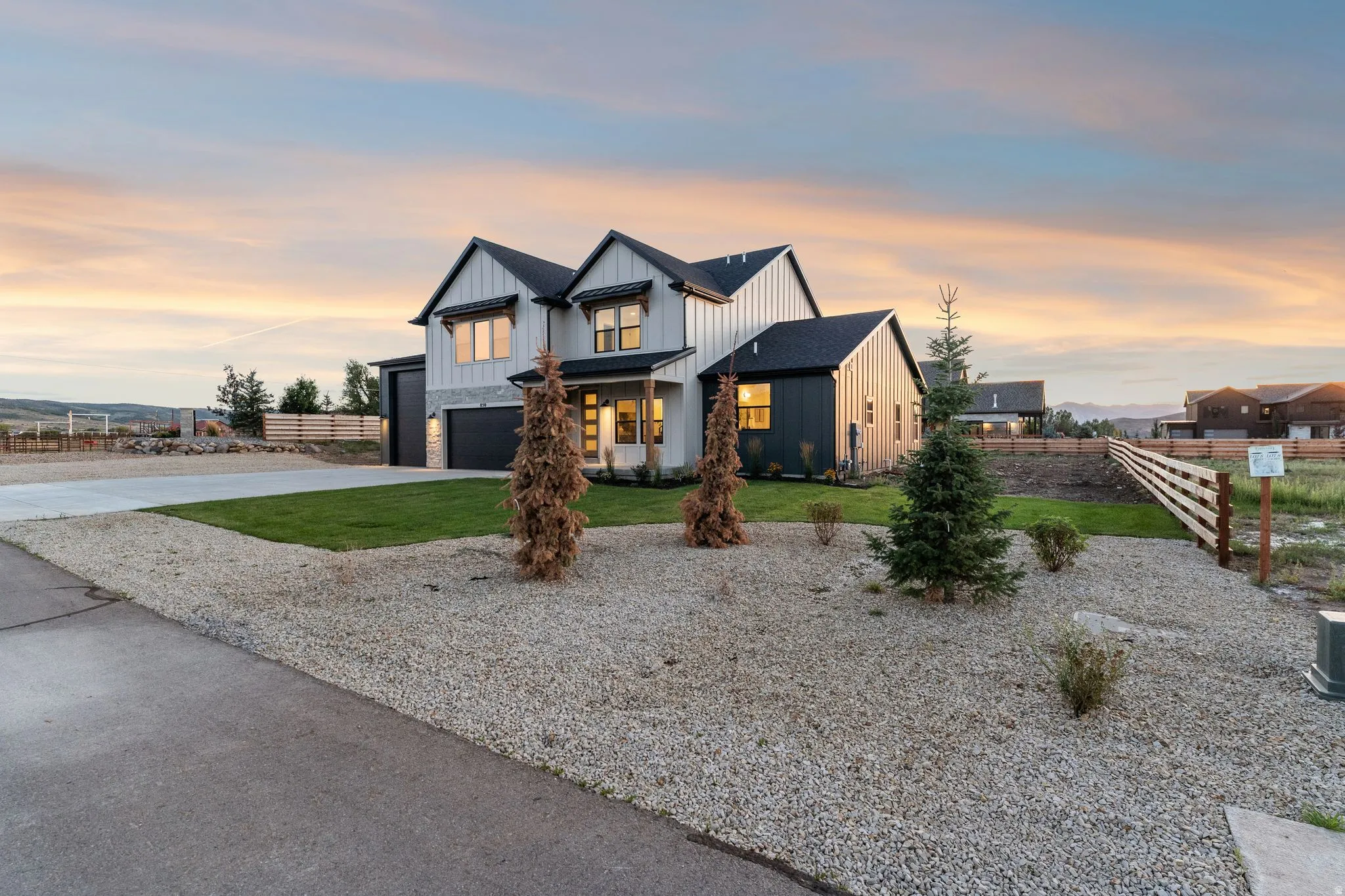 Modern farmhouse exterior with vertical white siding, stone accents, and a dark asphalt shingle roof