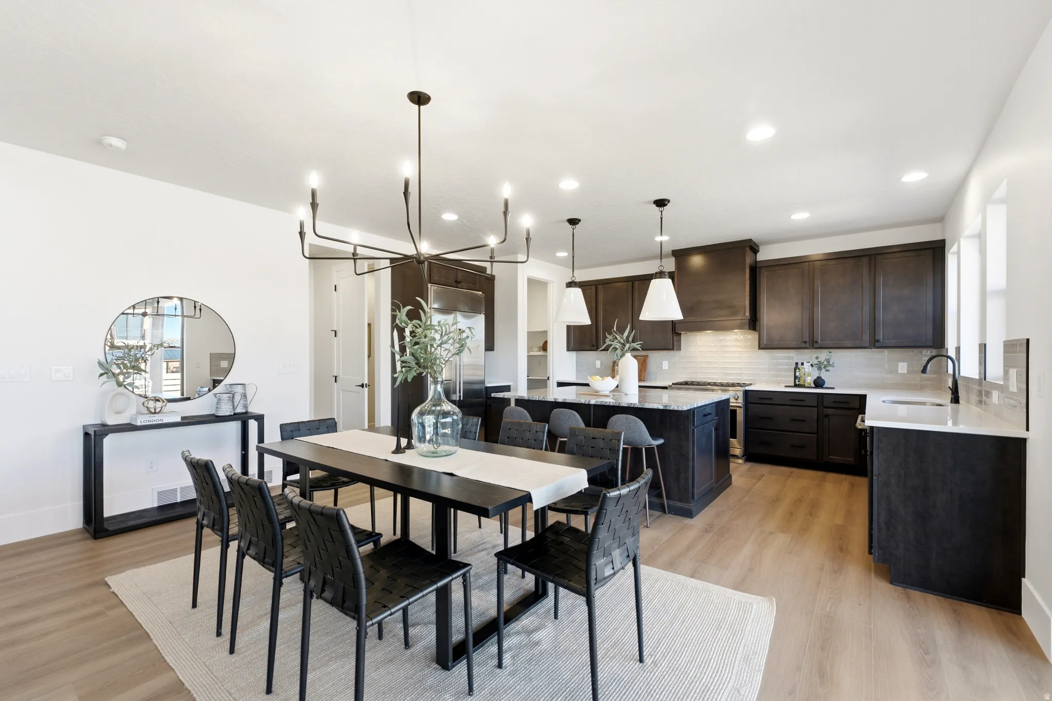 Spacious kitchen featuring dark wood cabinetry, a large kitchen island with pendant lighting, a subway tile backsplash, and stainless steel appliances