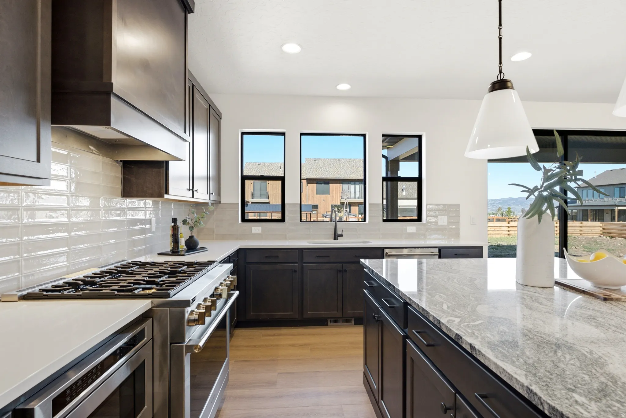 Gourmet kitchen with stainless steel range, dark wood cabinetry, light countertops, and a large kitchen island