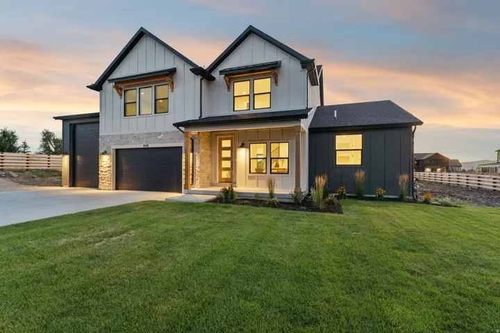 Contemporary exterior featuring board and batten siding, stone accents, black-framed windows, and a covered entry