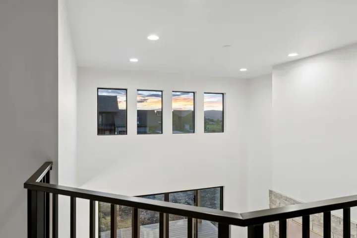 High ceilings featuring recessed lighting, a modern black metal railing, and multiple windows providing natural light