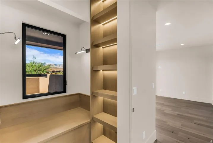 Built-in wood-finish shelving with integrated lighting, a built-in wood-finish bench, and a large window with a black frame