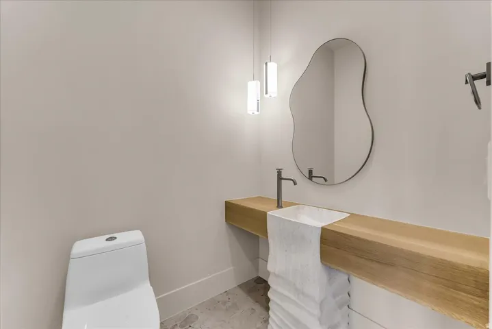 Floating wood vanity with integrated basin, matte black faucet, and organic-shaped mirror