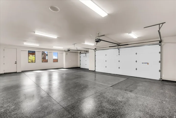 Spacious garage featuring a durable concrete floor, multiple garage doors, and abundant overhead lighting