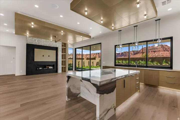 Spacious interior with wood-finish flooring, a waterfall island, and built-in cabinetry