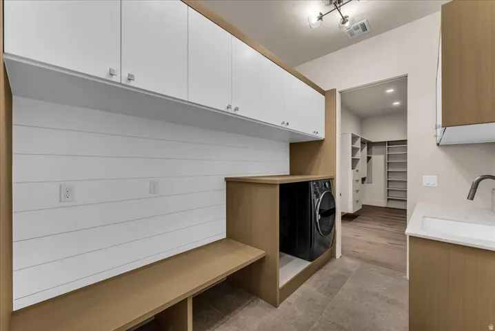 Wood-finish cabinetry, white flat-panel upper cabinets, white shiplap wall, built-in bench, and a built-in sink with a matte black faucet