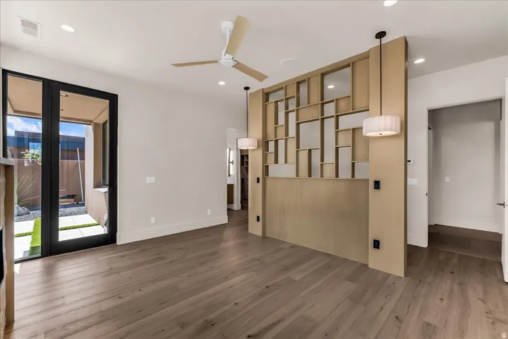 Wood-finish flooring throughout, featuring a decorative room divider with integrated pendant lighting and a modern ceiling fan
