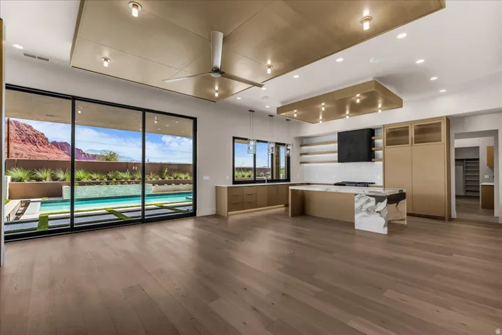 Wood-finish flooring throughout, with a contemporary ceiling fan, recessed lighting, and expansive glass sliding doors