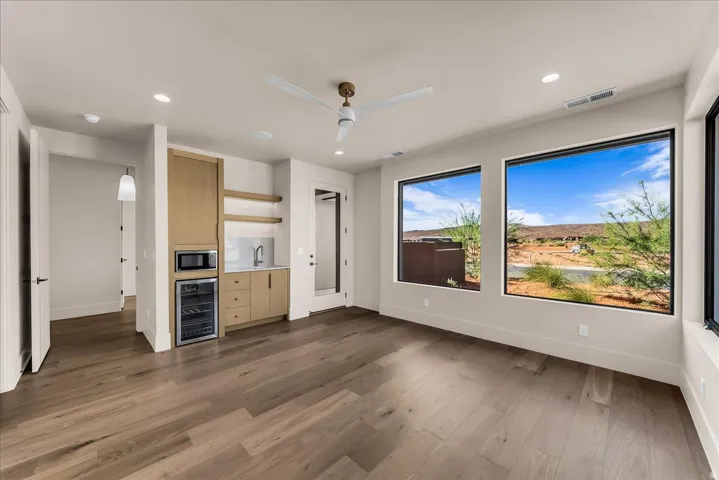 Wood-finish flooring, recessed lighting, and a built-in wet bar with a wine refrigerator and microwave