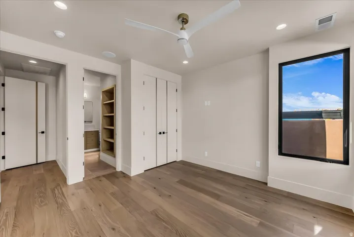 Wide plank wood-finish flooring, recessed lighting, and a contemporary ceiling fan