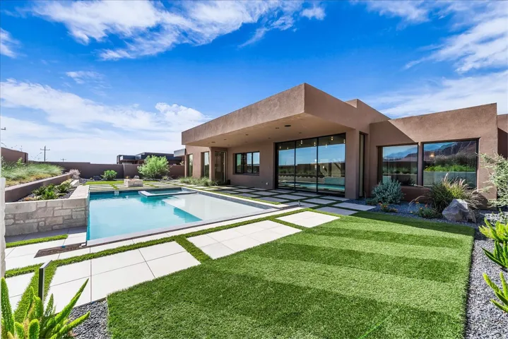 Modern exterior architecture featuring a geometric swimming pool, extensive patio, and manicured lawn