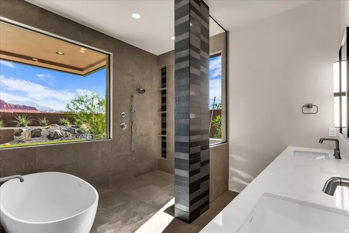 Freestanding bathtub, expansive picture window, dual vanity with undermount sinks, and a walk-in shower with integrated shelving