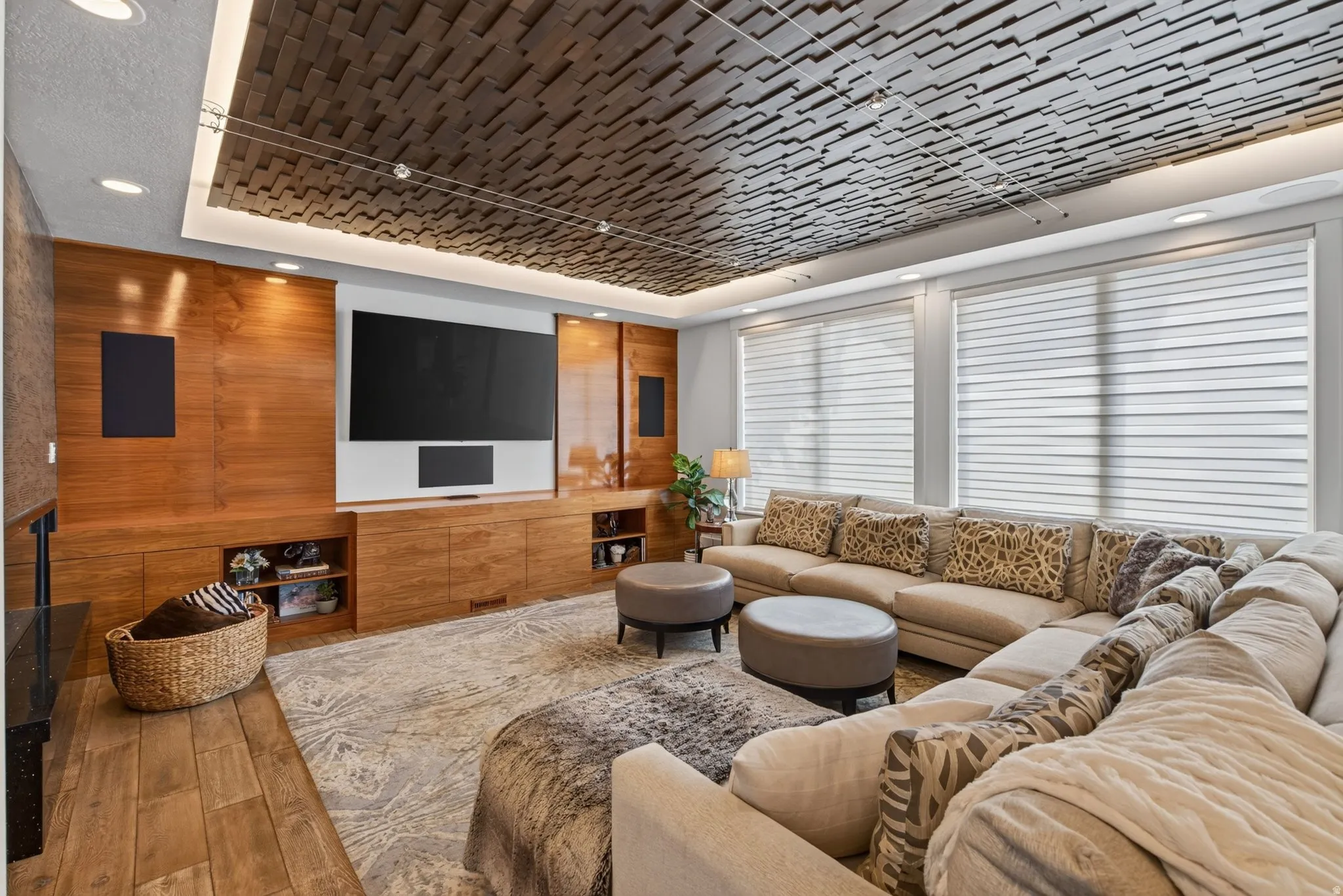 Wood-finish flooring, custom wood-paneled media wall, recessed lighting, and a textured ceiling detail