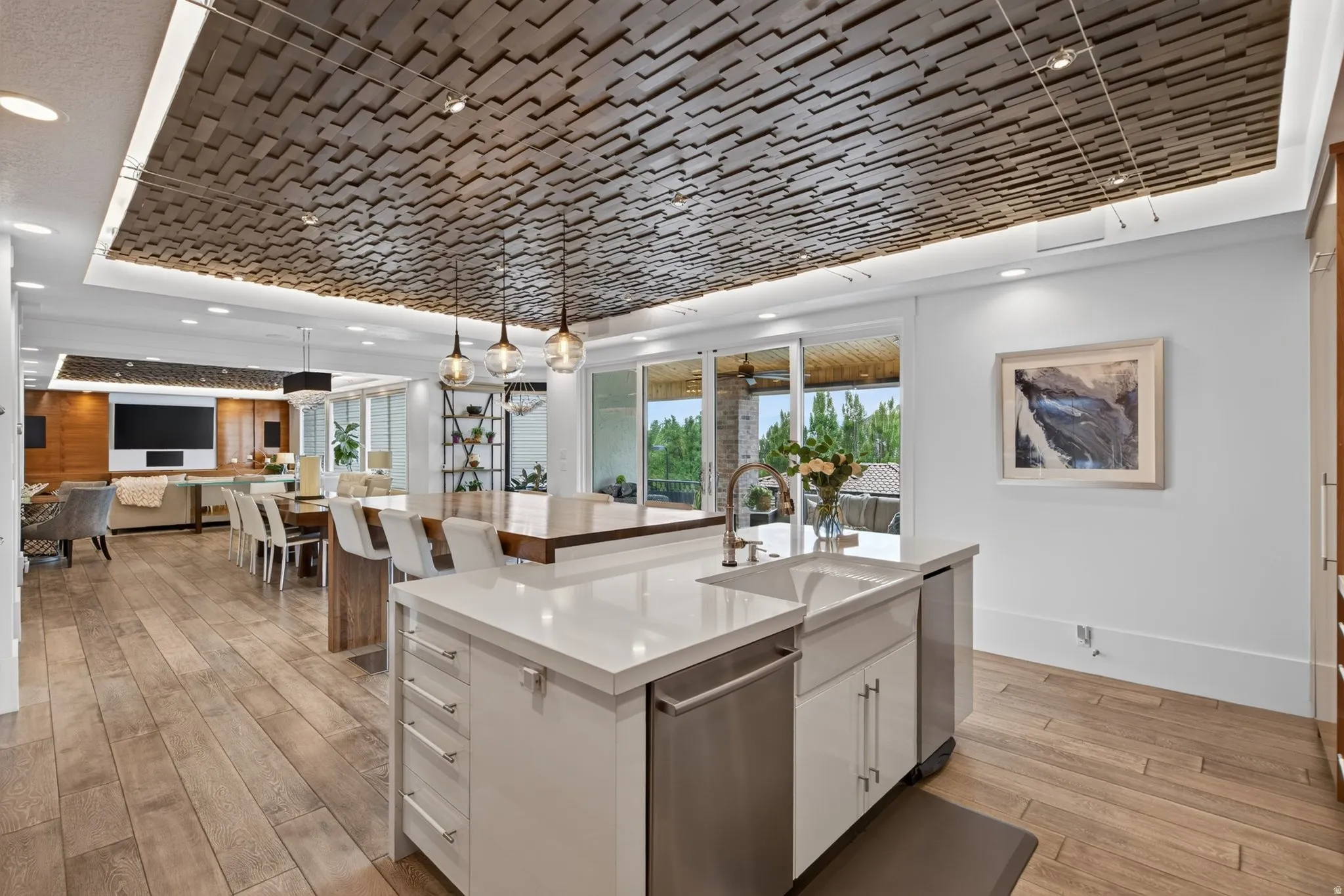 Open-concept living space featuring wood-finish flooring, a kitchen island with a farmhouse sink, and a decorative wood ceiling panel with recessed lighting