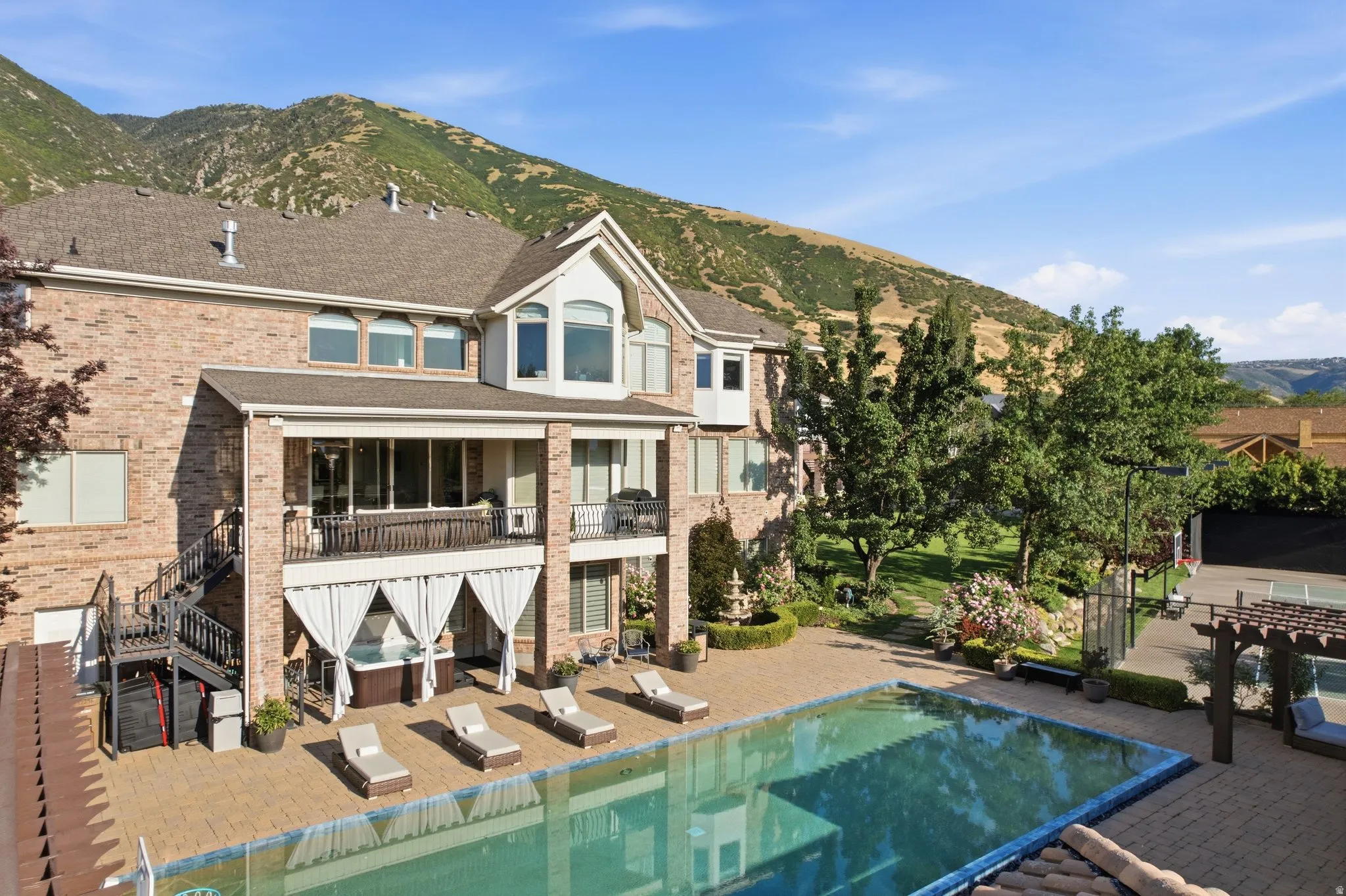 Brick exterior with multiple balconies, an outdoor pool, and an integrated spa
