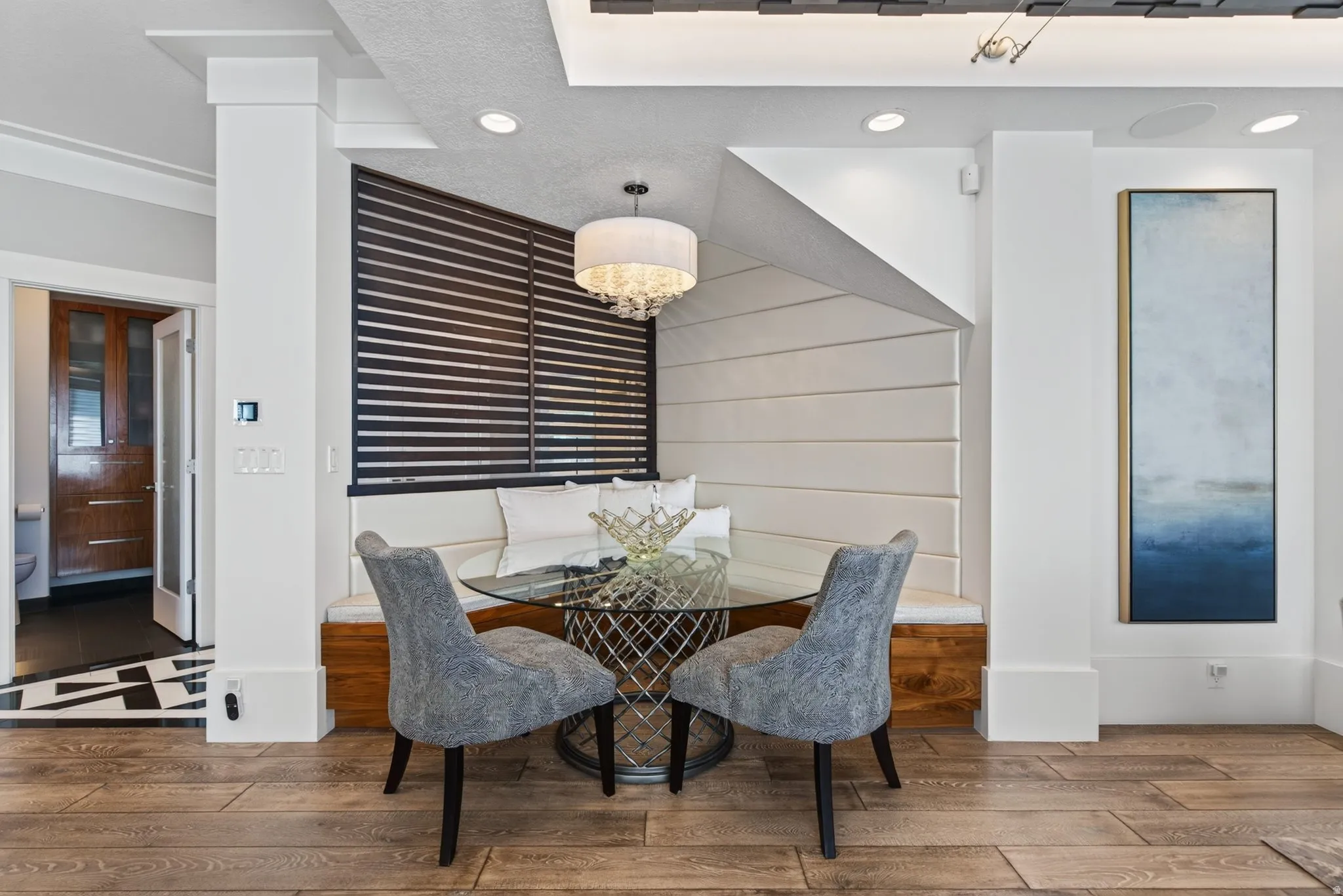 Built-in banquette seating, wood-finish flooring, recessed lighting, and a contemporary chandelier