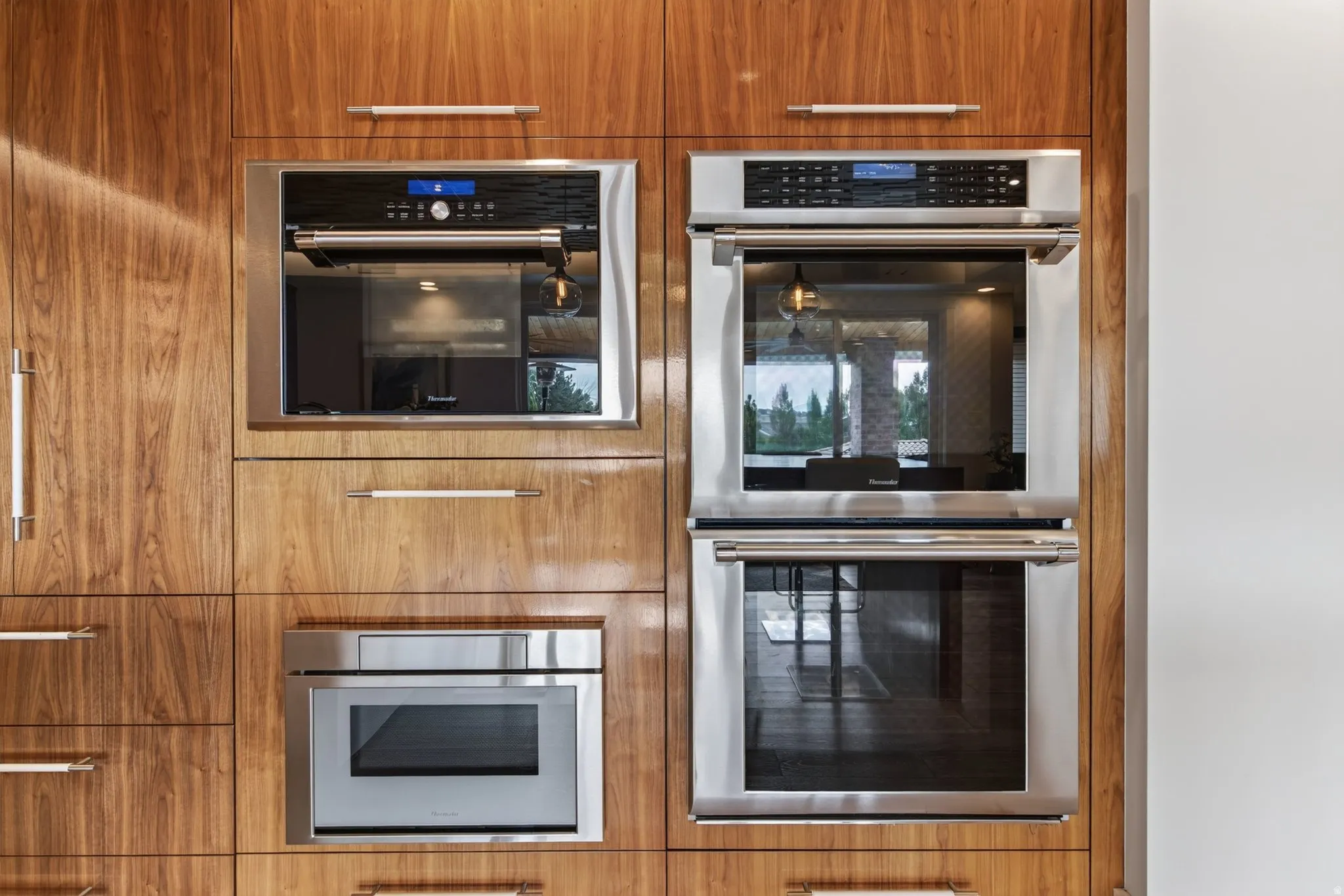 Integrated wall ovens, built-in microwave, integrated warming drawer, and wood-finish cabinetry