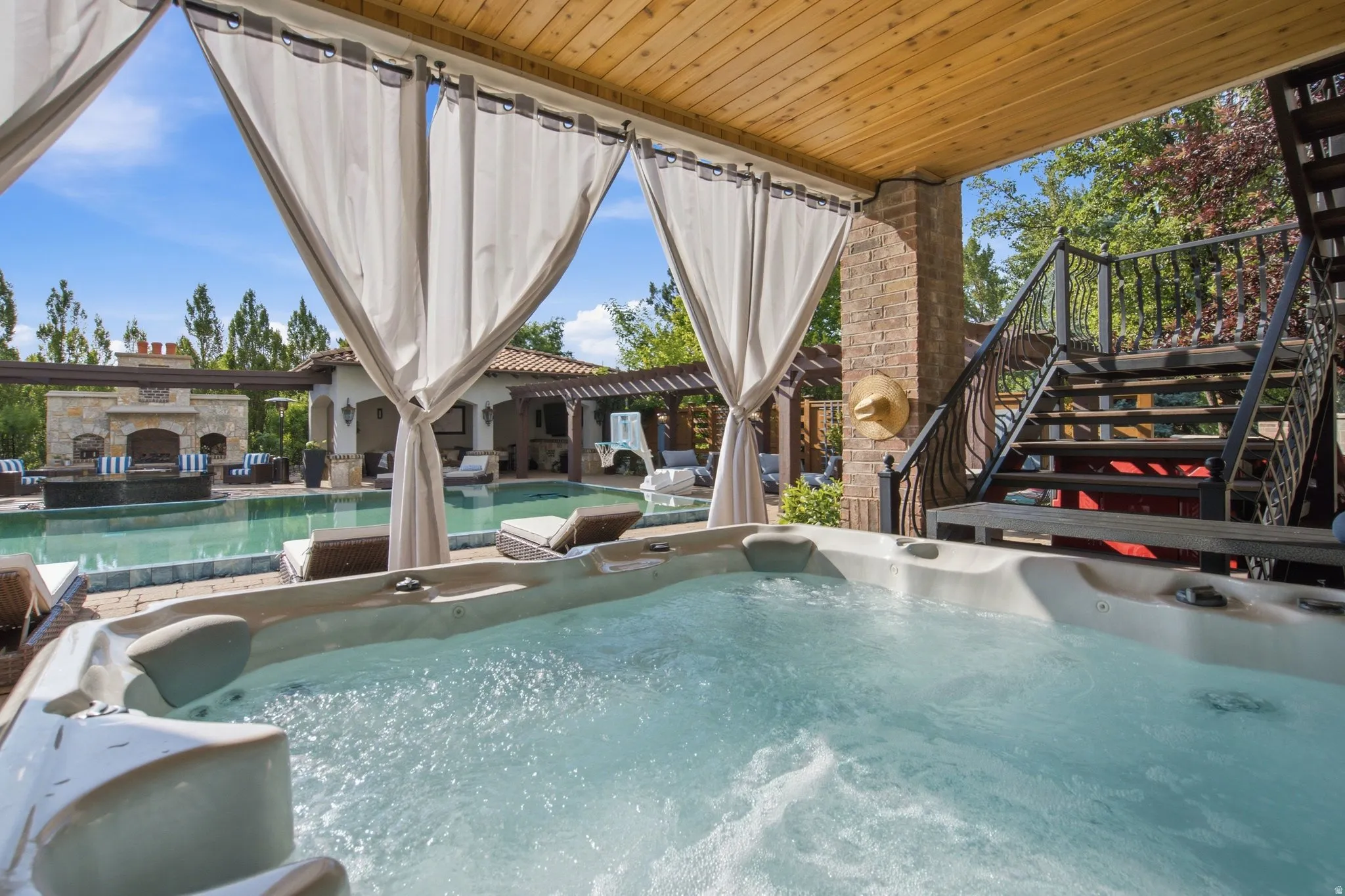 Outdoor spa with bubbling water, brick pillar, and a wood plank ceiling
