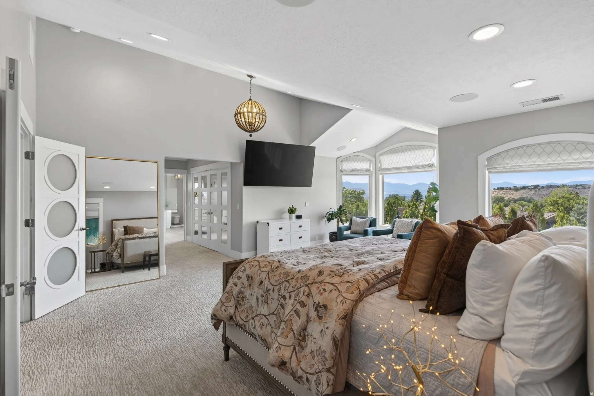 Vaulted ceilings, recessed lighting, large windows with arched tops, and light-colored carpeting