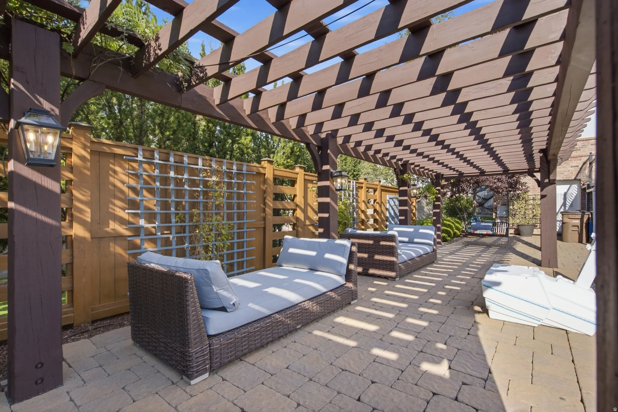 Expansive outdoor pergola structure with integrated lighting, brick paver patio, and wood fencing