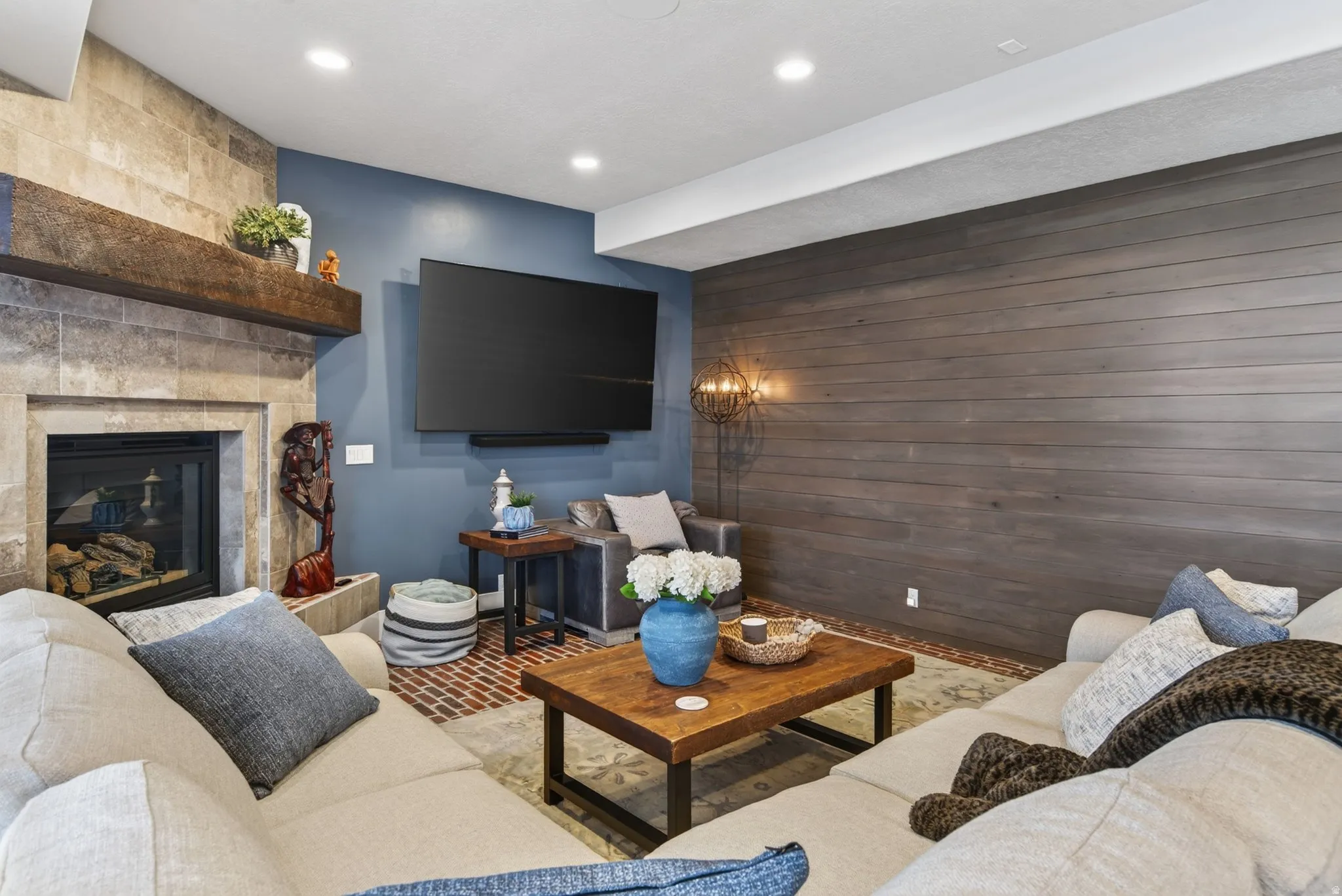 Recessed lighting illuminating a shiplap accent wall, a built-in fireplace with a stone surround, and a wood mantel