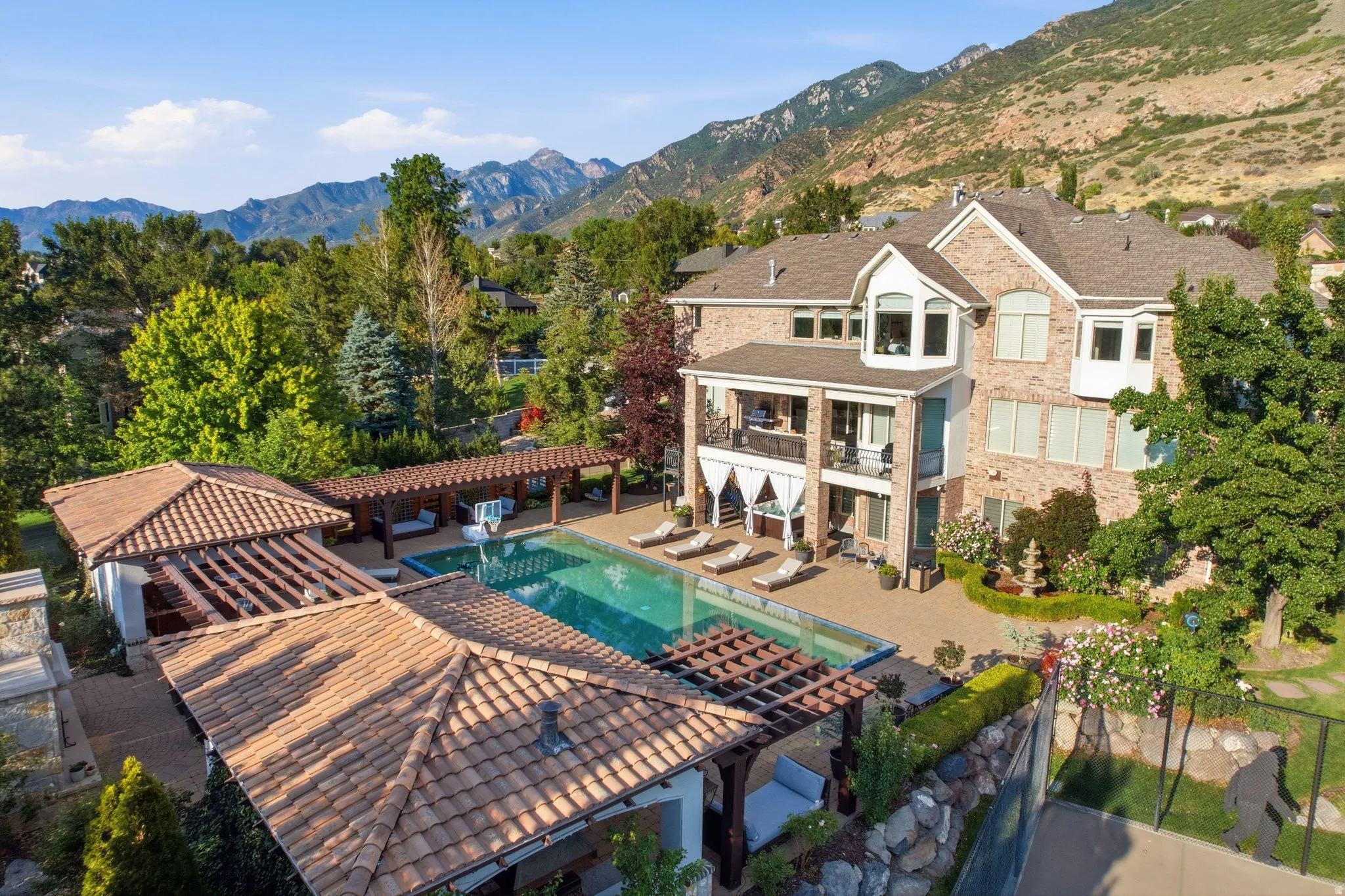 Brick exterior with multiple bay windows, extensive patio with an in-ground pool, two covered pergolas, and a separate covered structure with a tile roof