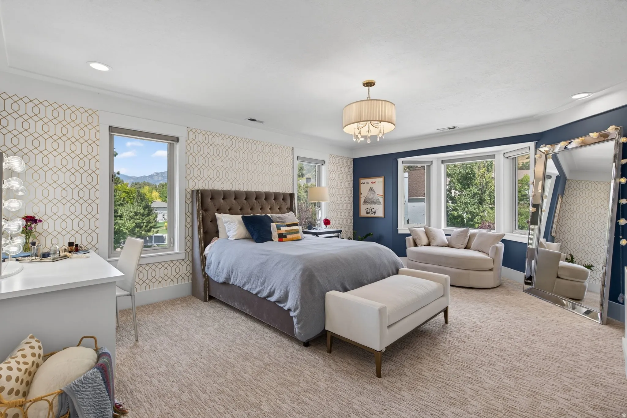 Recessed lighting, patterned accent walls, tray ceiling, drum chandelier, and a bay window