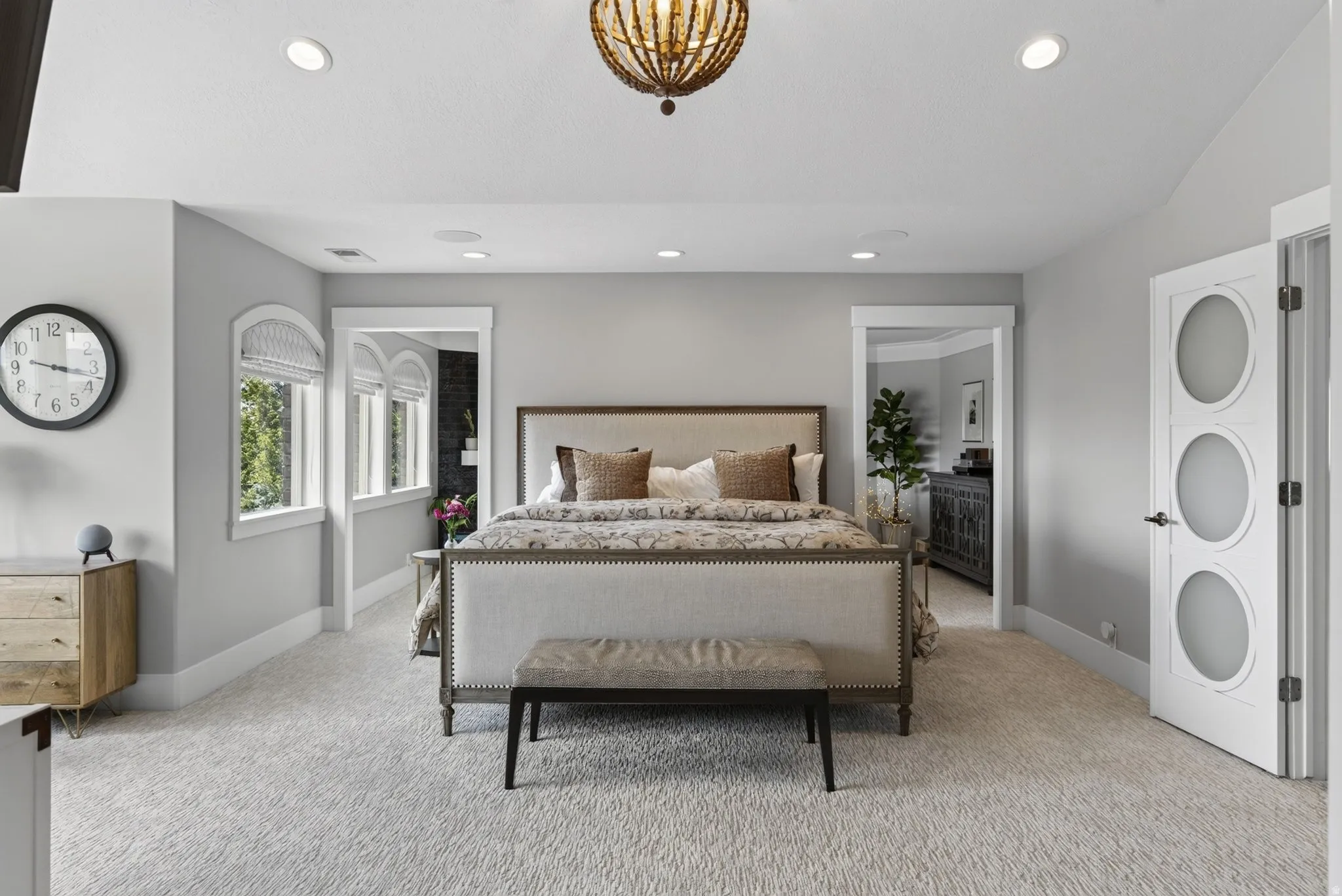 Recessed ceiling lighting, vaulted ceiling, arched windows, decorative interior door with frosted glass inserts, and a beaded chandelier