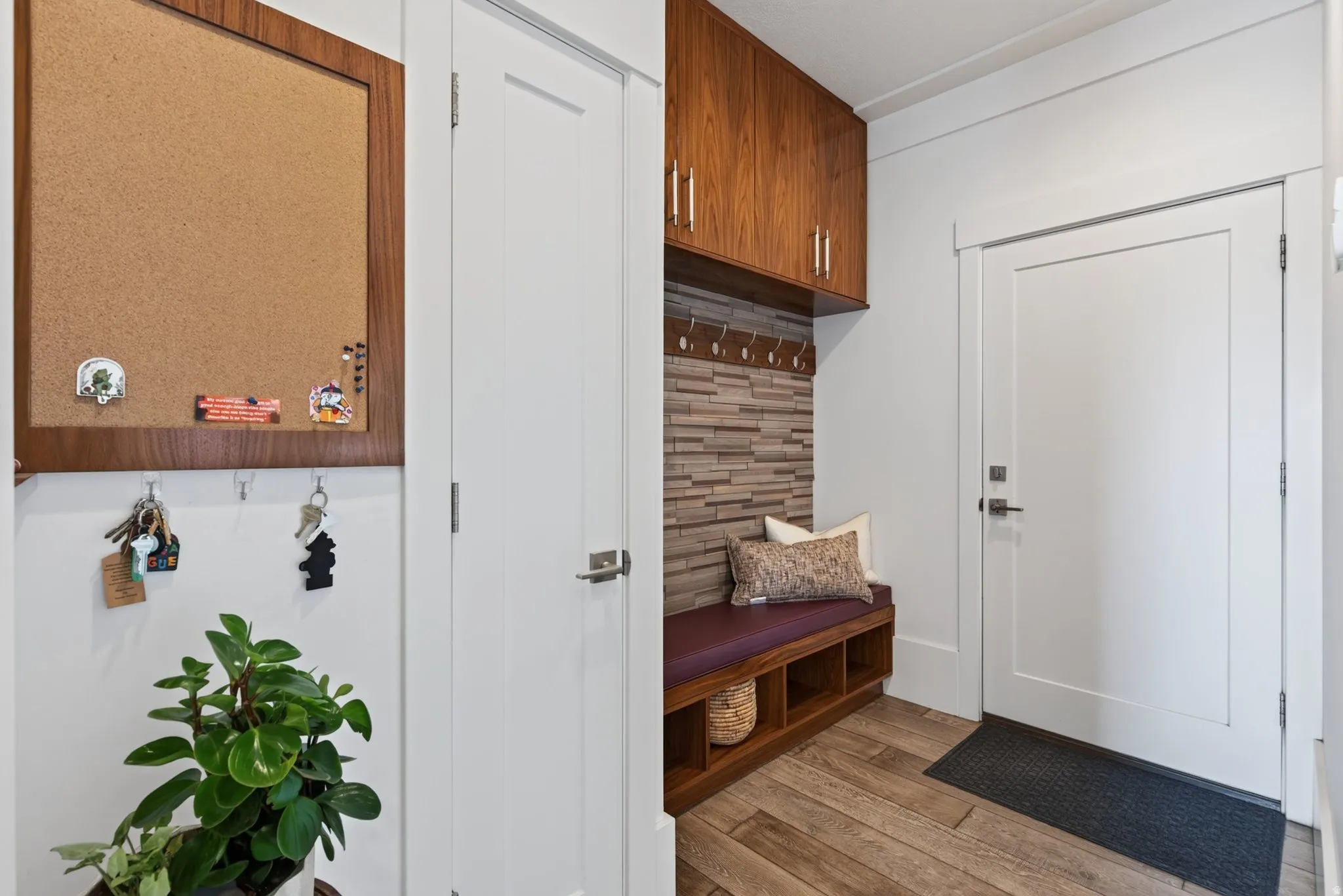 Built-in entryway bench with storage cubbies, wood-finish flooring, and a textured wall accent