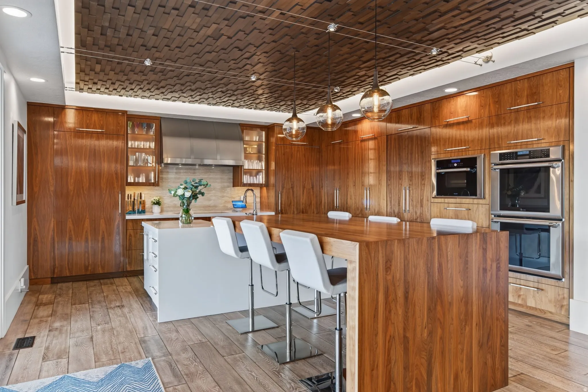 Custom wood-paneled kitchen featuring integrated appliances, a central island with wood countertop, and a textured ceiling