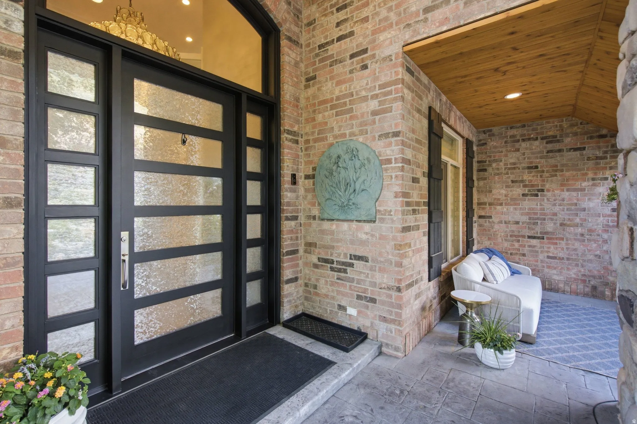 Brick exterior with stone accents, a multi-paneled front door, an arched transom window, and a wood-paneled porch ceiling