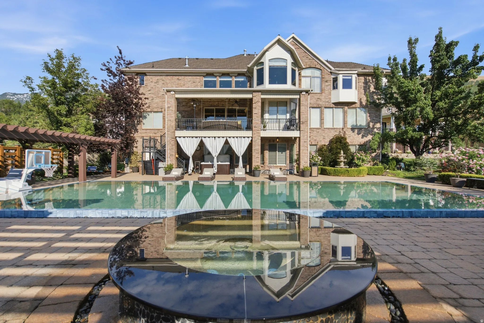 Brick exterior, multi-level balconies, expansive pool, paver patio, and integrated water feature