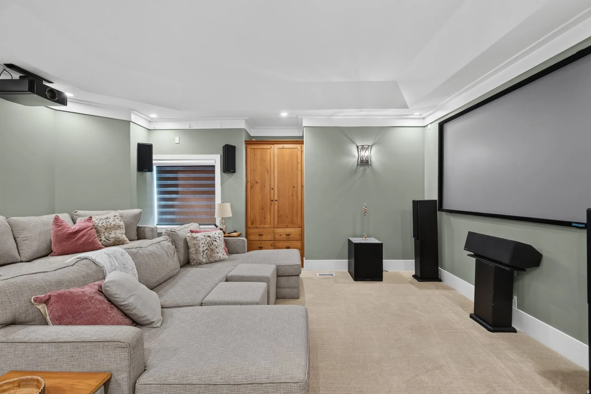 Integrated projection screen, ceiling-mounted projector, wall-mounted speakers, recessed lighting, and crown molding
