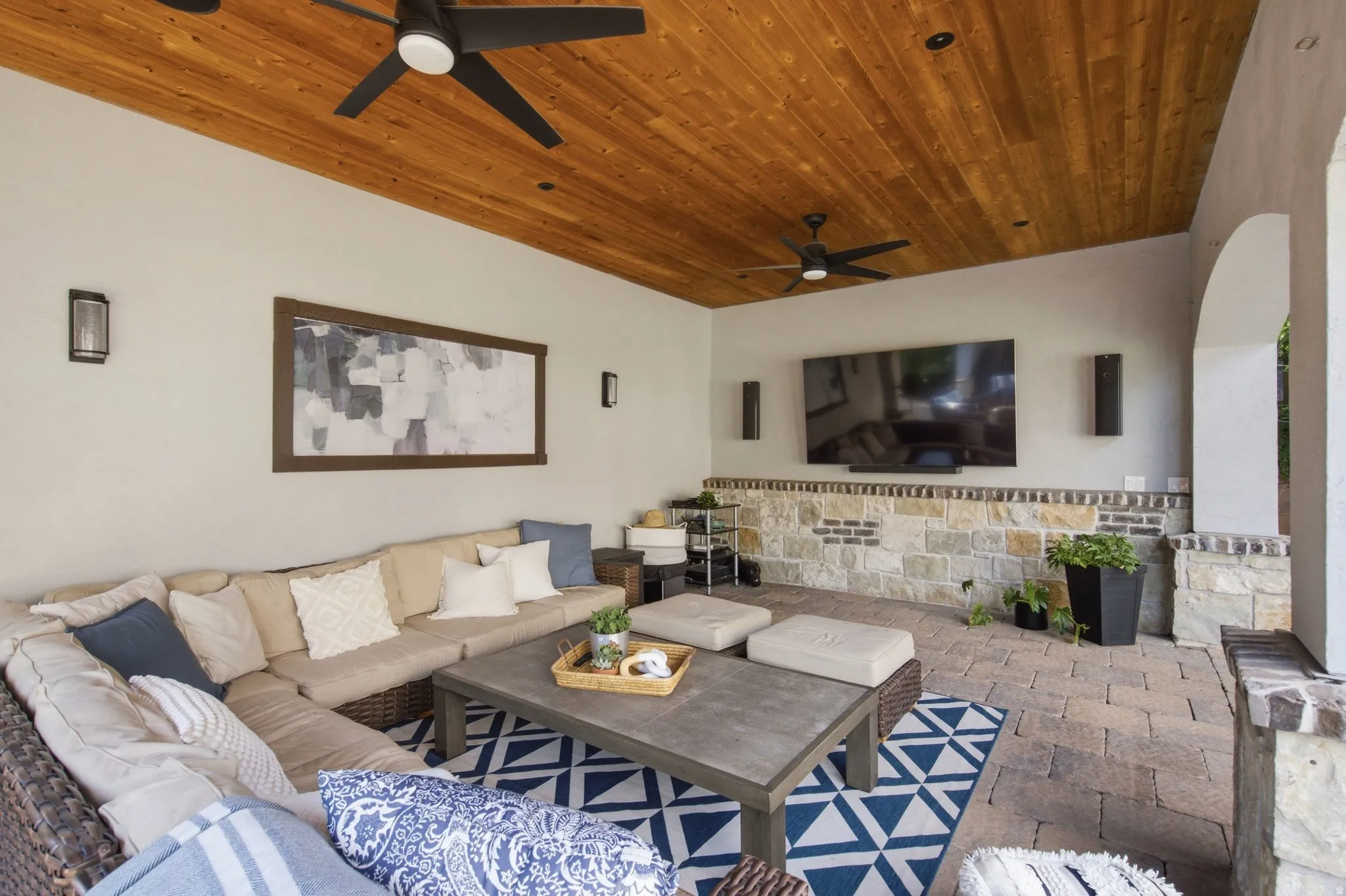 Covered outdoor living space featuring a wood-panel ceiling, recessed lighting, and dual ceiling fans