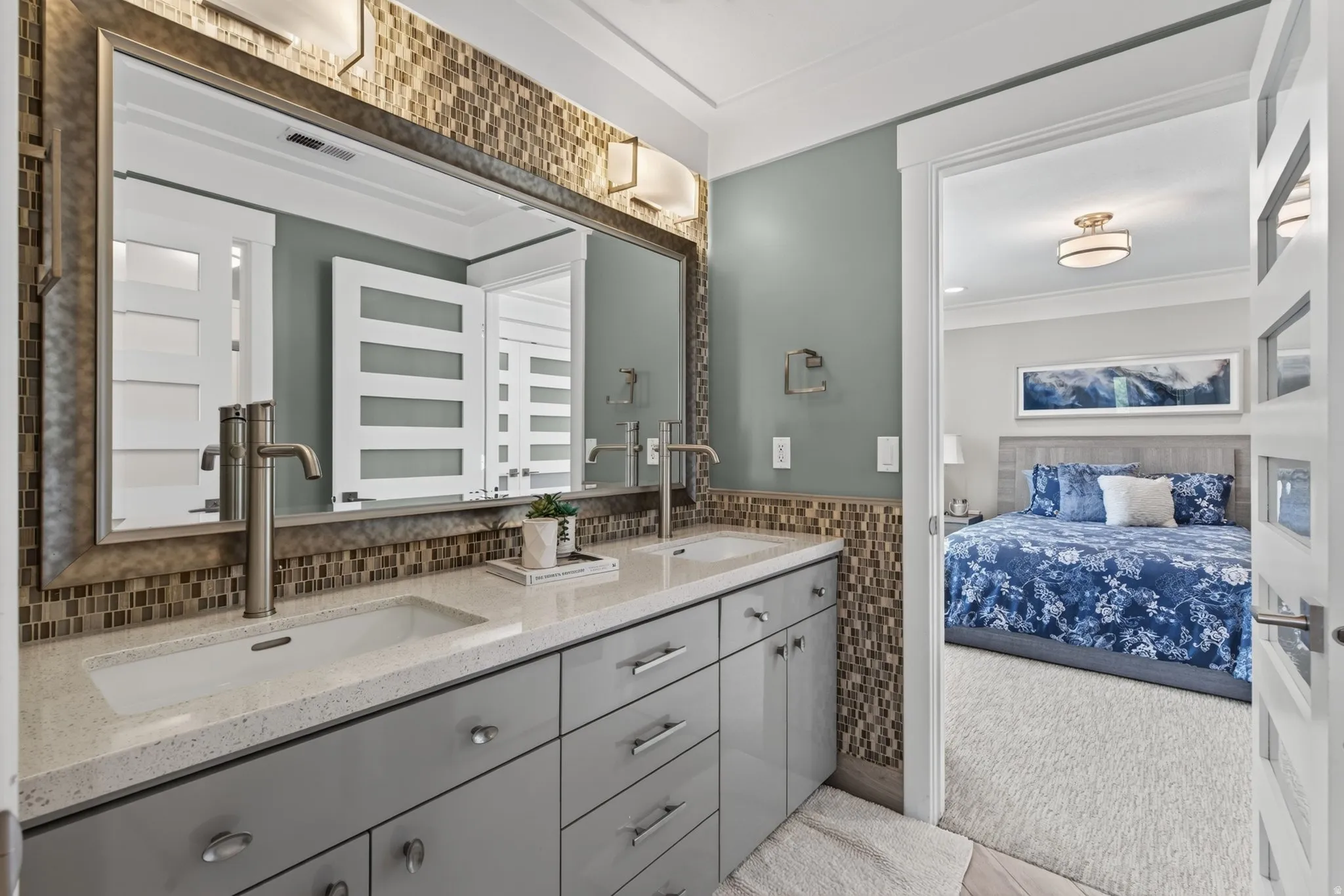 Dual vanity with sleek gray cabinetry, contemporary faucets, and a mosaic tile backsplash