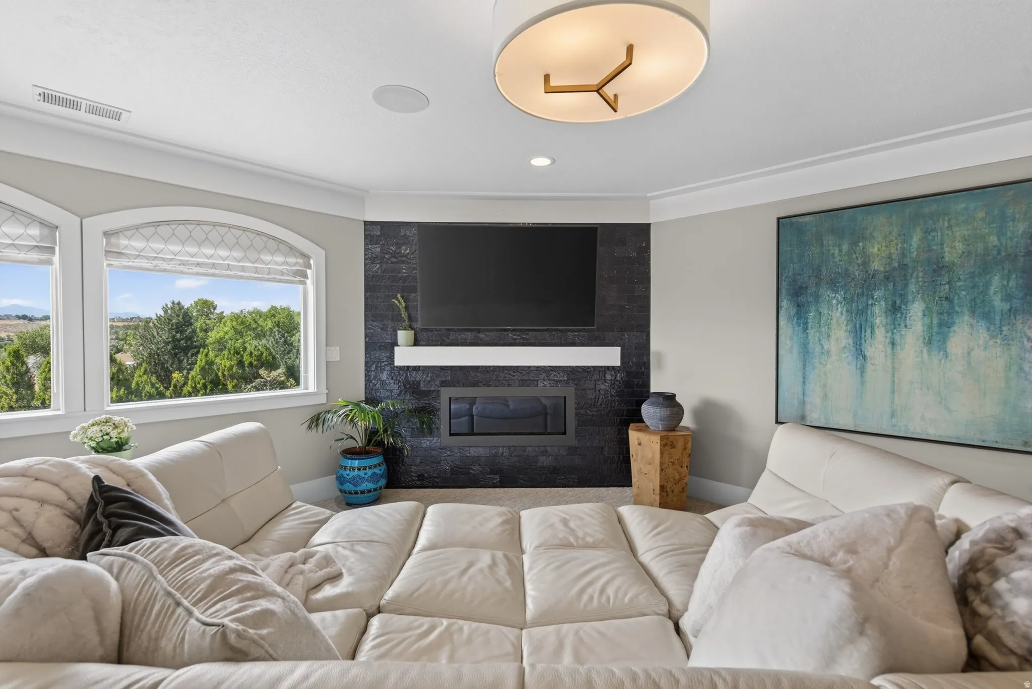 Recessed lighting, contemporary chandelier, gas fireplace with a dark tile surround, integrated built-in shelving, and arched windows