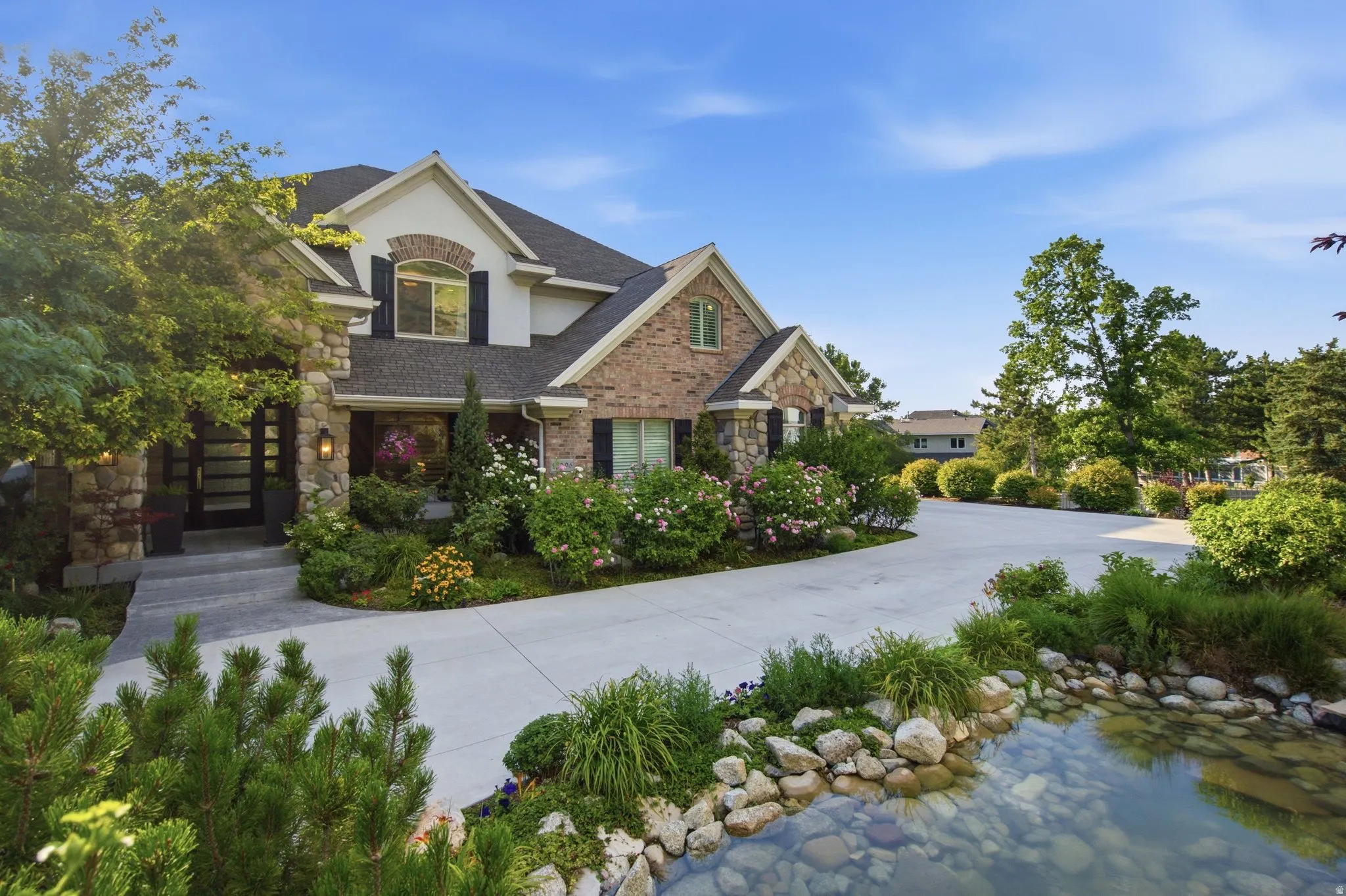 Stone and brick exterior with contrasting black shutters, an arched window, and a concrete driveway