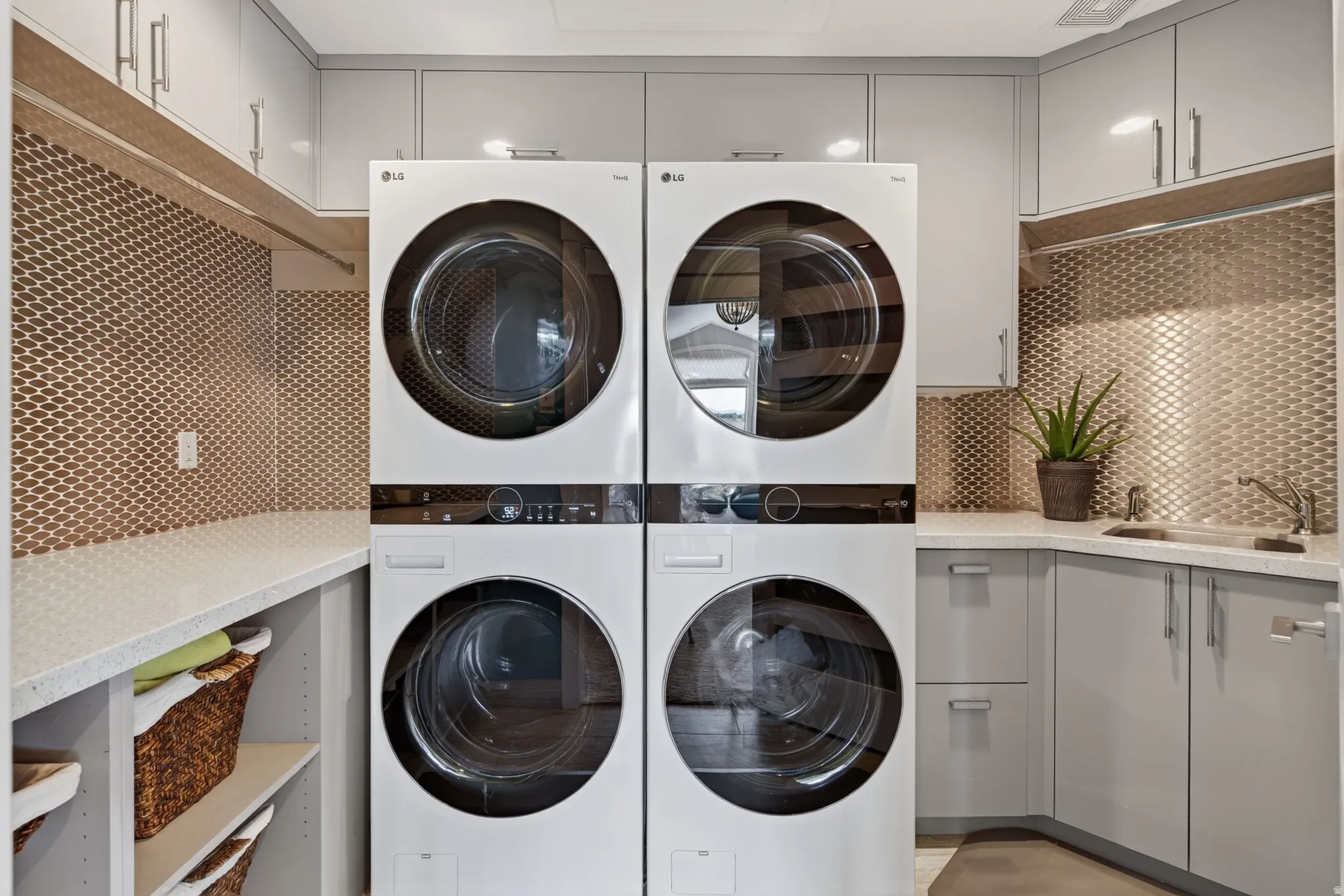 Integrated washer and dryer units, extensive built-in cabinetry, durable countertops, a stainless steel utility sink, and a unique metallic backsplash