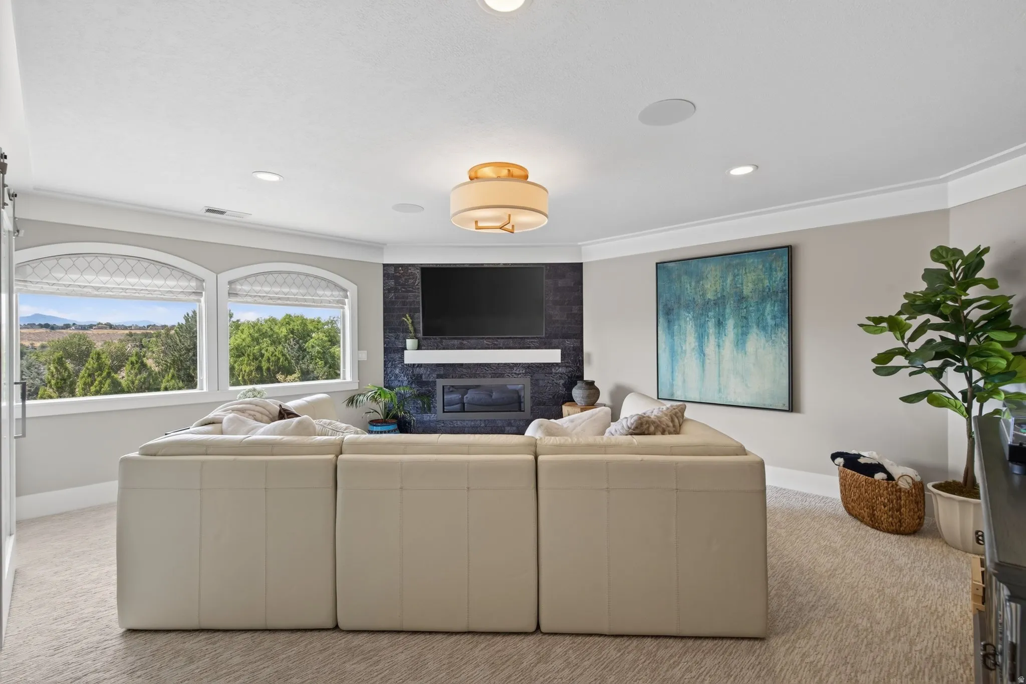 Recessed lighting, crown molding, and a built-in fireplace with a stone surround